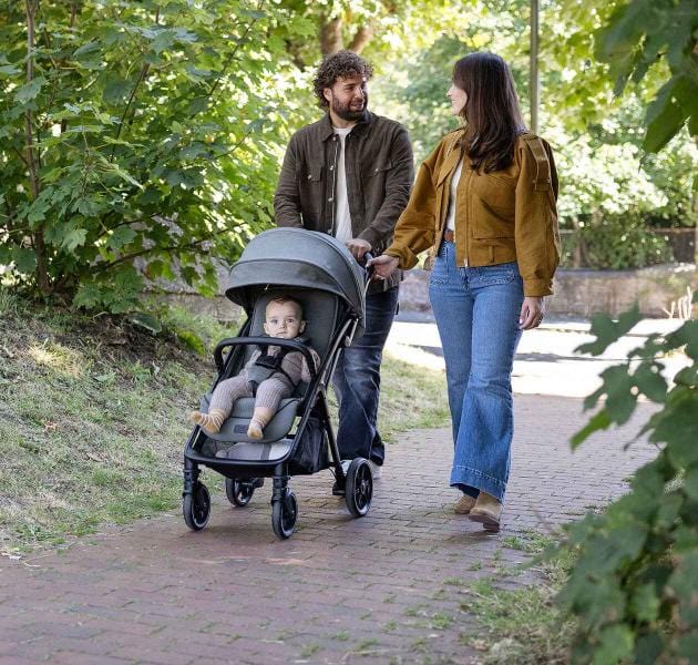 Parent pushing stroller along pavement with child seated inside