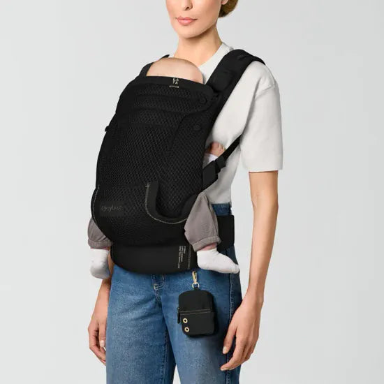 Parent carrying baby in inward-facing front position in the Cybex Laya Baby Carrier in Black, with storage pouch clipped to waist belt