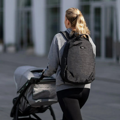 Parent wearing the Thule Changing Backpack whilst pushing a Thule pushchair