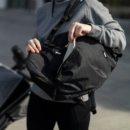 Parent opening the Thule Changing Backpack whilst out with a pushchair