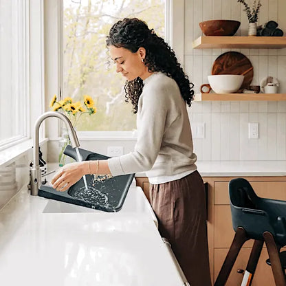 Parent rinsing the UPPAbaby Ciro V2 tray liner under the kitchen tap